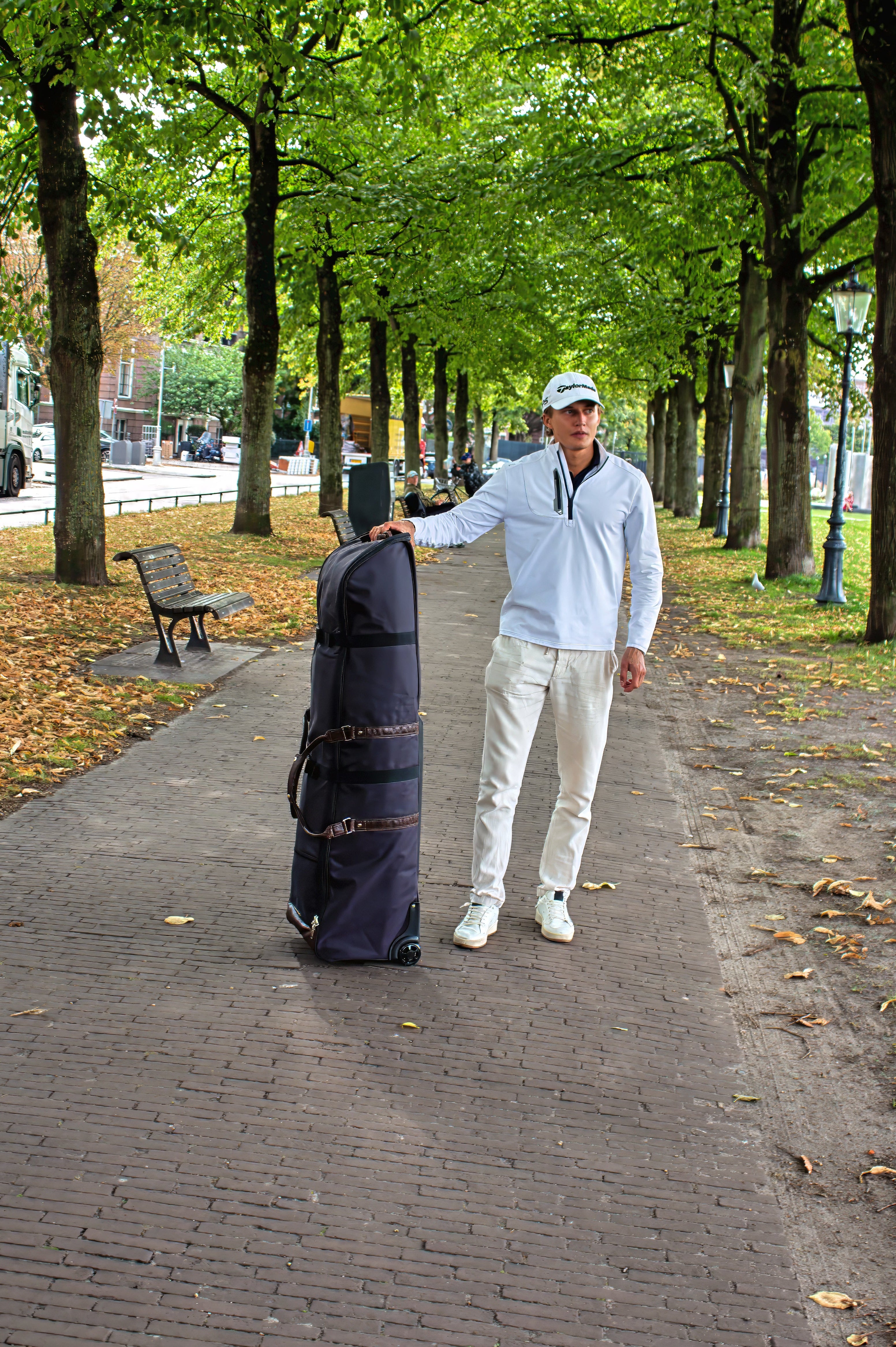Man standing in a park with the John Martin Golf Travel Bag.